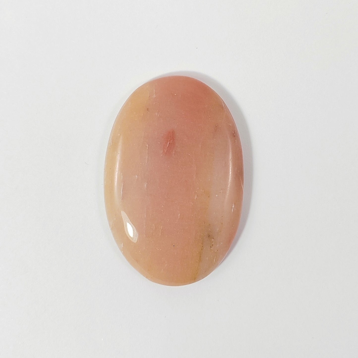 Oval-shaped peach-colored stone on a white background