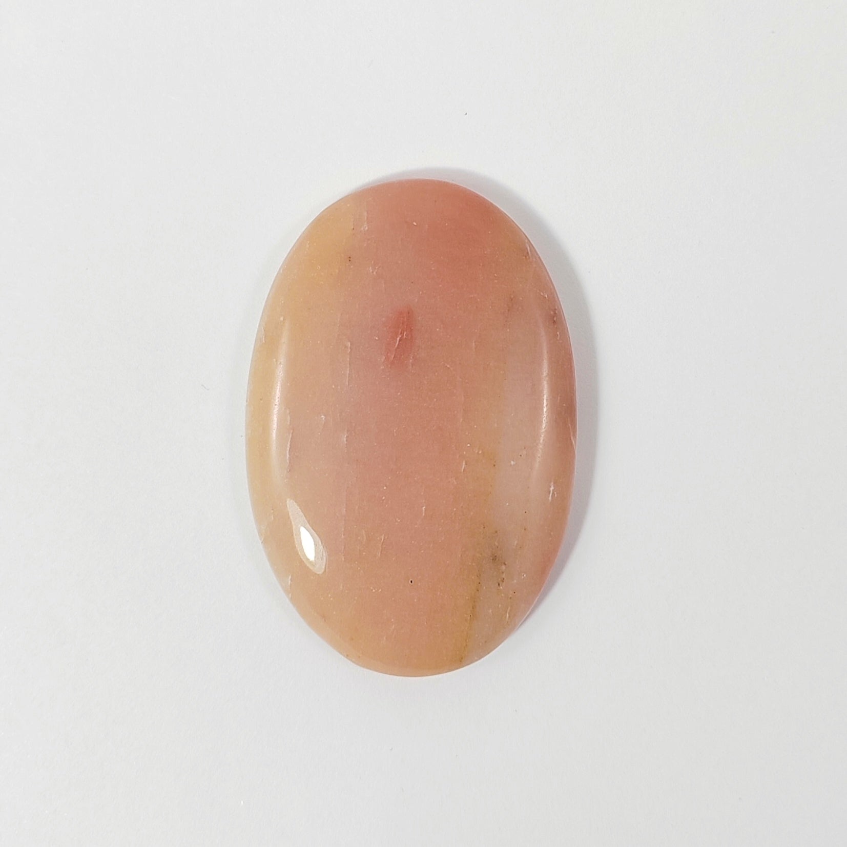 Oval-shaped peach-colored stone on a white background