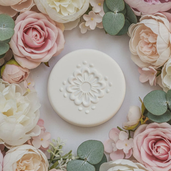 A round,  stamp with a raised floral mandala design.