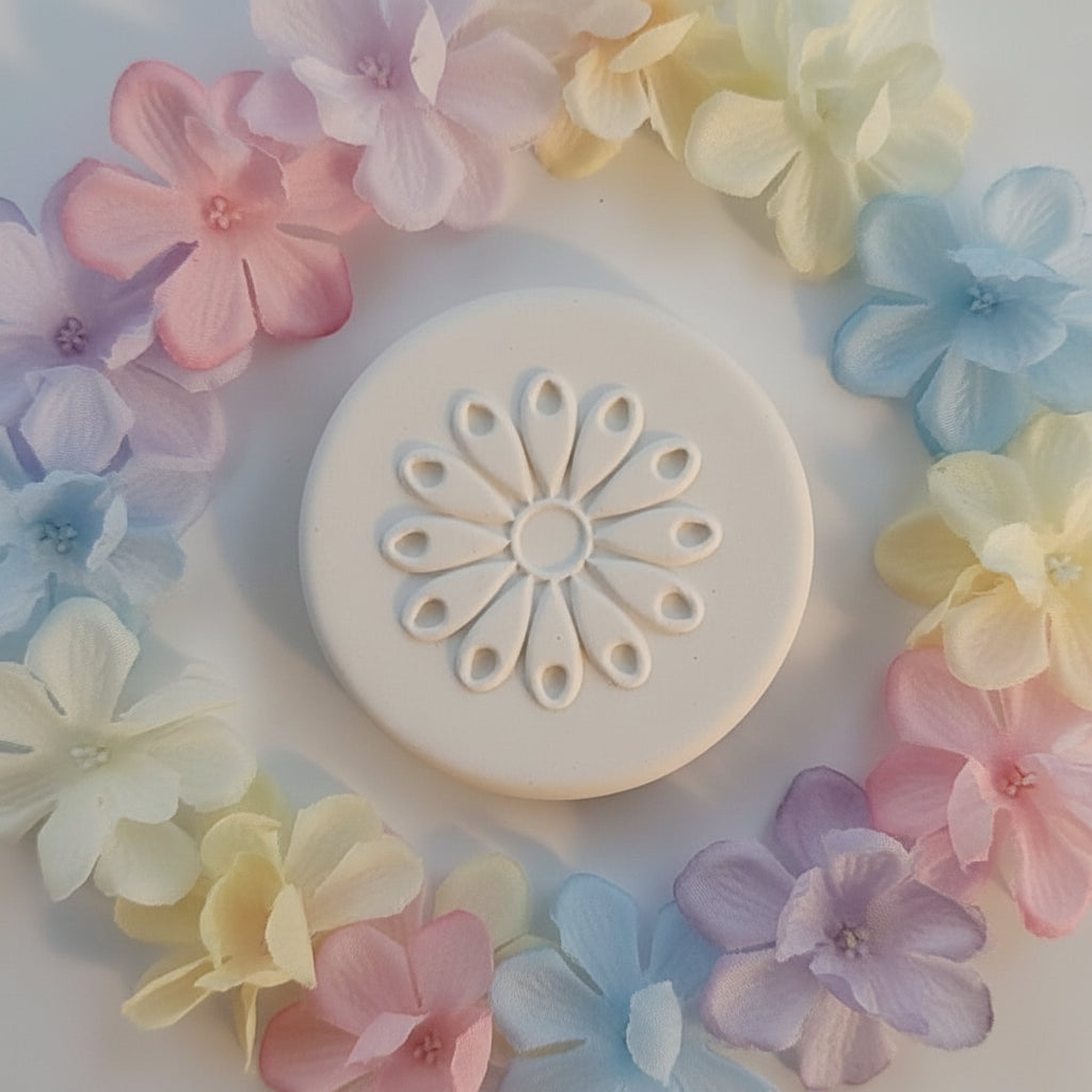 A round clay stamp featuring a raised floral petal pattern.
