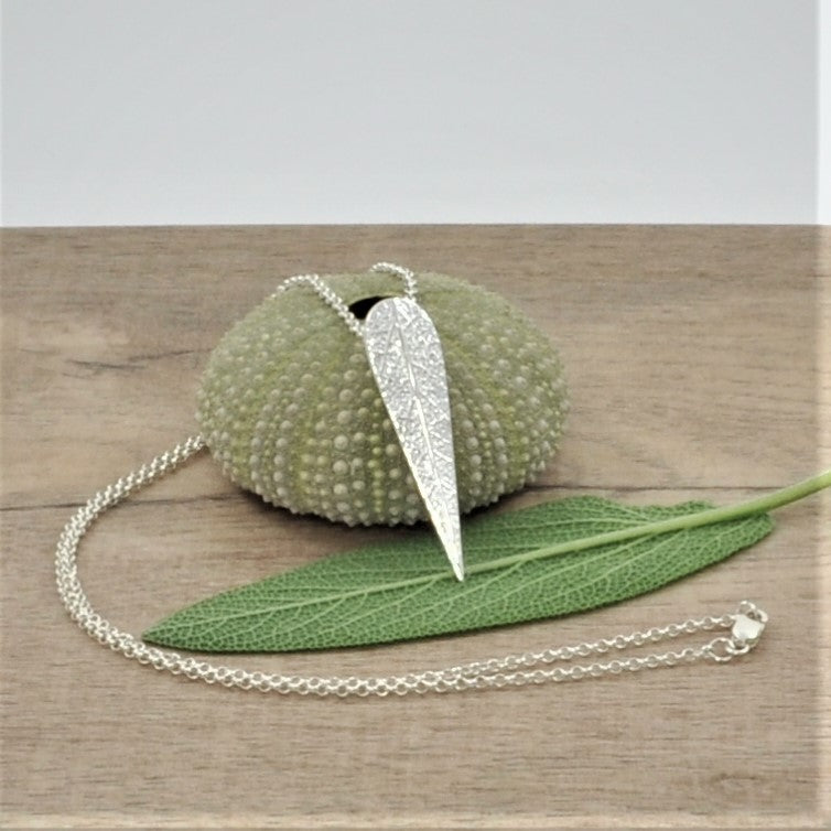 This elegant necklace features a delicately textured 999 fine silver sage leaf pattern attached to a P bail and suspended on a 925 sterling trace chain, fastened to the neck with a 925 lobster clasp. Crafted with expertise and care, this necklace is sure to last a lifetime and make a truly special gift. Length of leaf necklace is 260mm (length of chain + leaf) Chain length is 17.5 inches & chain link size is 1.6mm. It weighs 5.5g in total (including the chain). 