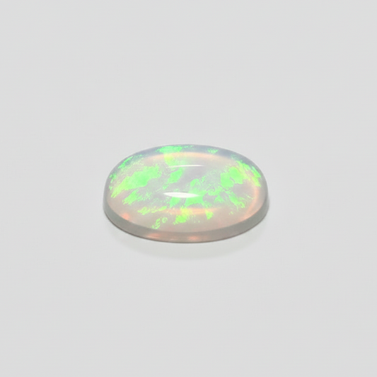 A small, oval-shaped cabochon gemstone with a milky white base and vibrant green iridescent flashes, displayed on a clean, light gray background.