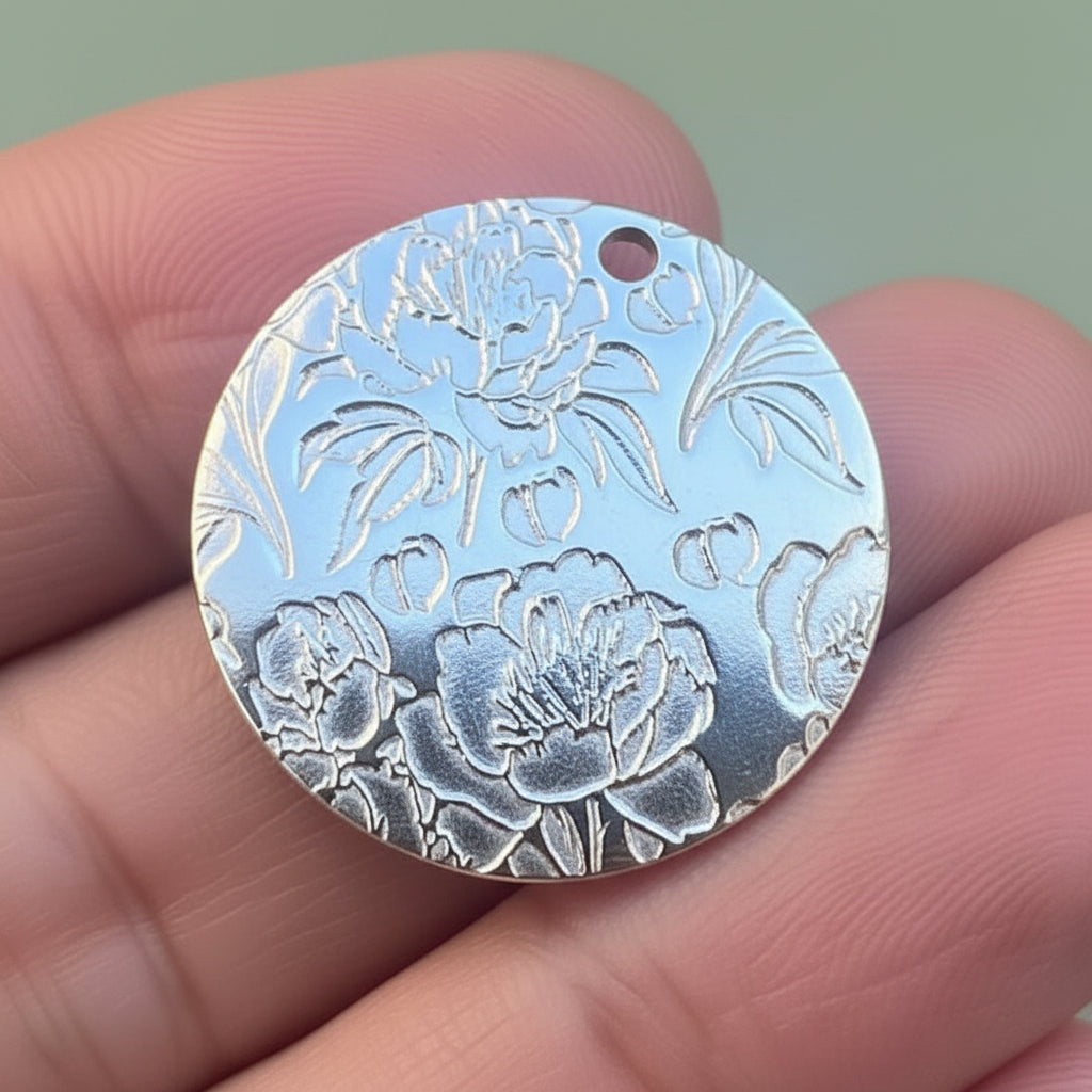Silver floral pendant held between fingers with a blurred background