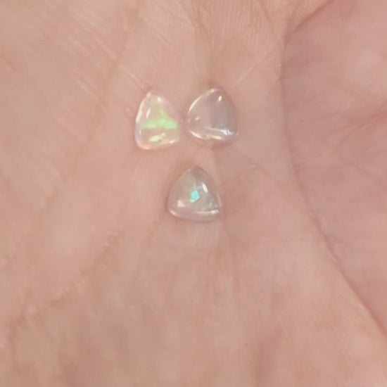 Three water opals with green fire displayed with a hand showing the green flash
