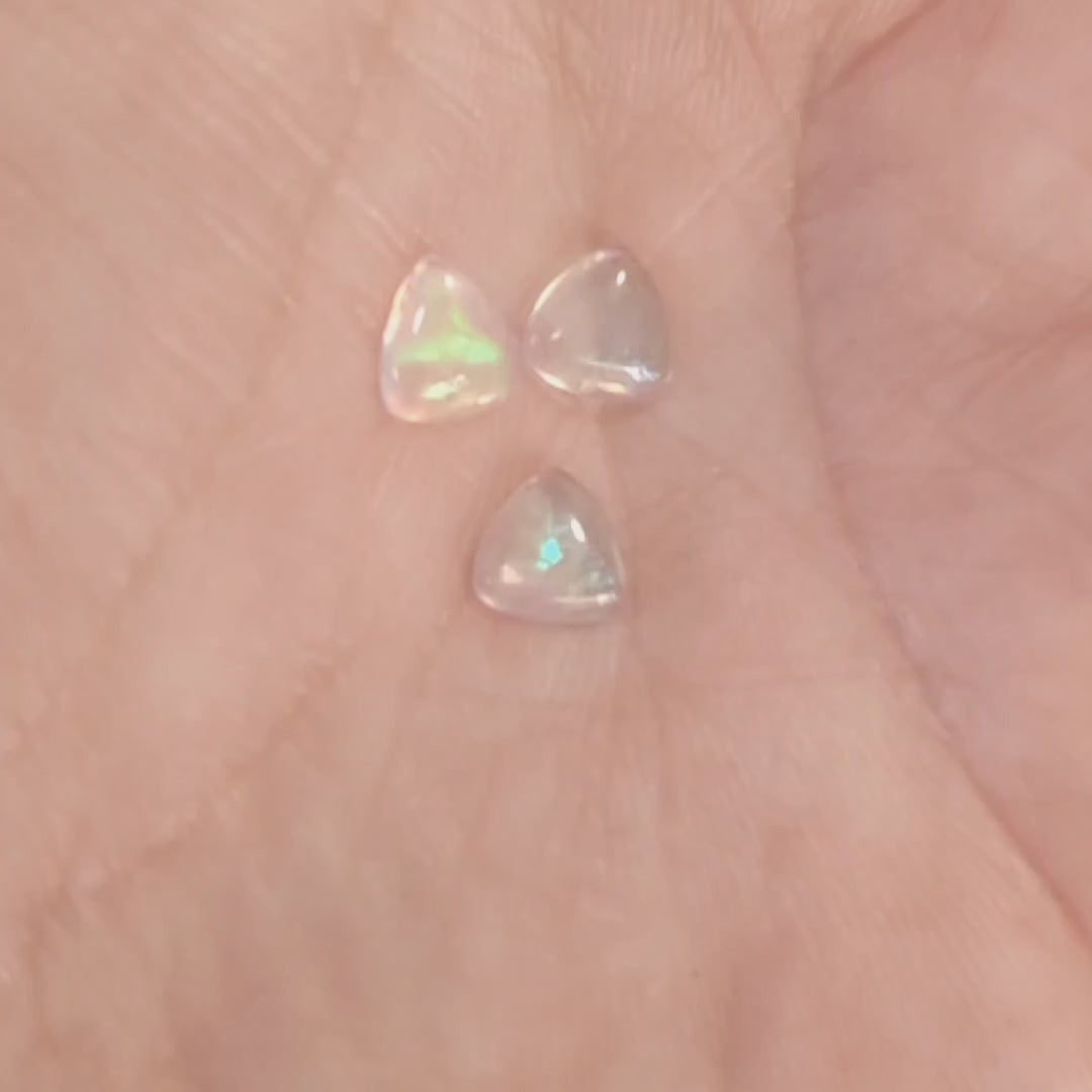 Three water opals with green fire displayed with a hand showing the green flash