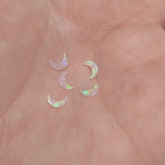 Five moon shaped fireable opals displaying the flash of green fire on a hand.