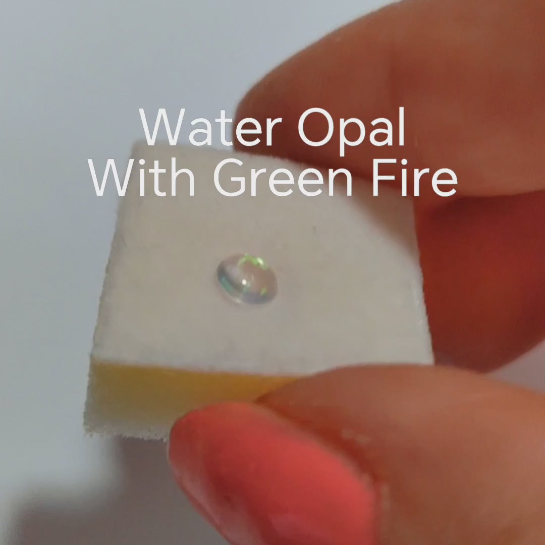 Fireable water opal with green Fire held in a hand on a Jewellery sponge.