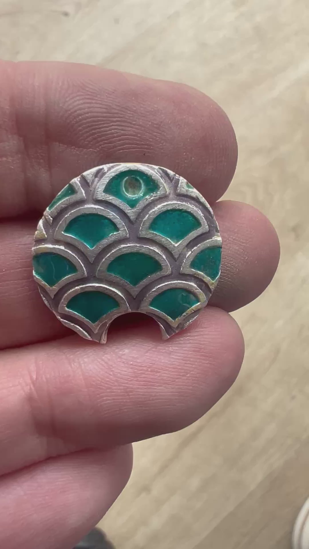 Video of fish scales debossed texture with transparent enamels on it.