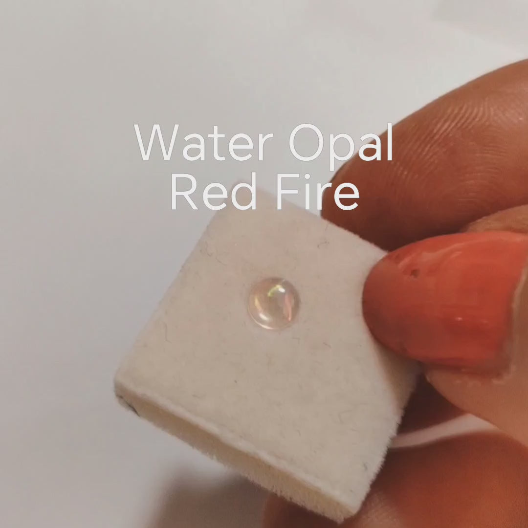 Fireable water opal with red fire on a jewellery sponge in a hand.