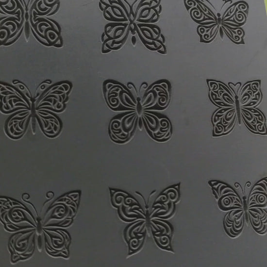 Nine butterfly textures debossed on grey rubber. Three rows of three. Pressed into metal clay to leave a debossed impression.