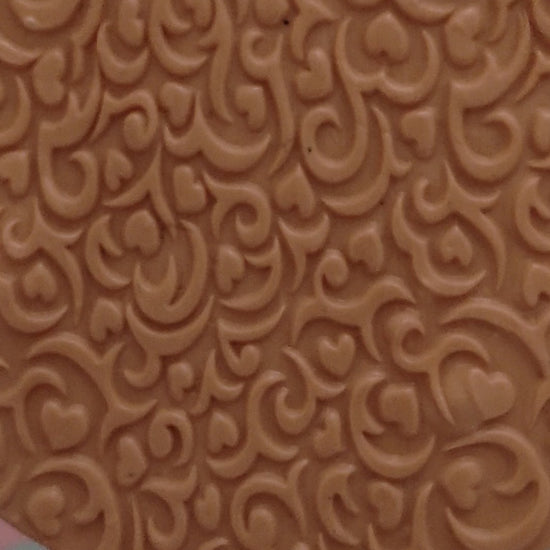 A swirly embossed pattern of hearts and lines In silly putty.