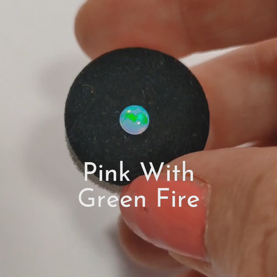 Opal Pink with green fire cabochons on a a jewellery sponge held in a hand