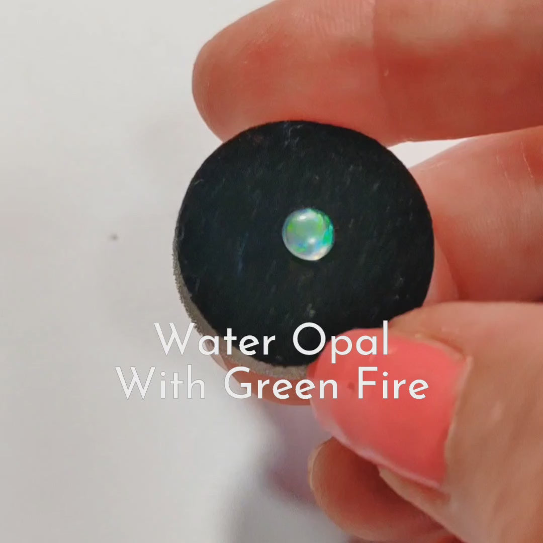 Fireable water opal with green Fire held in a hand on a Jewellery sponge.
