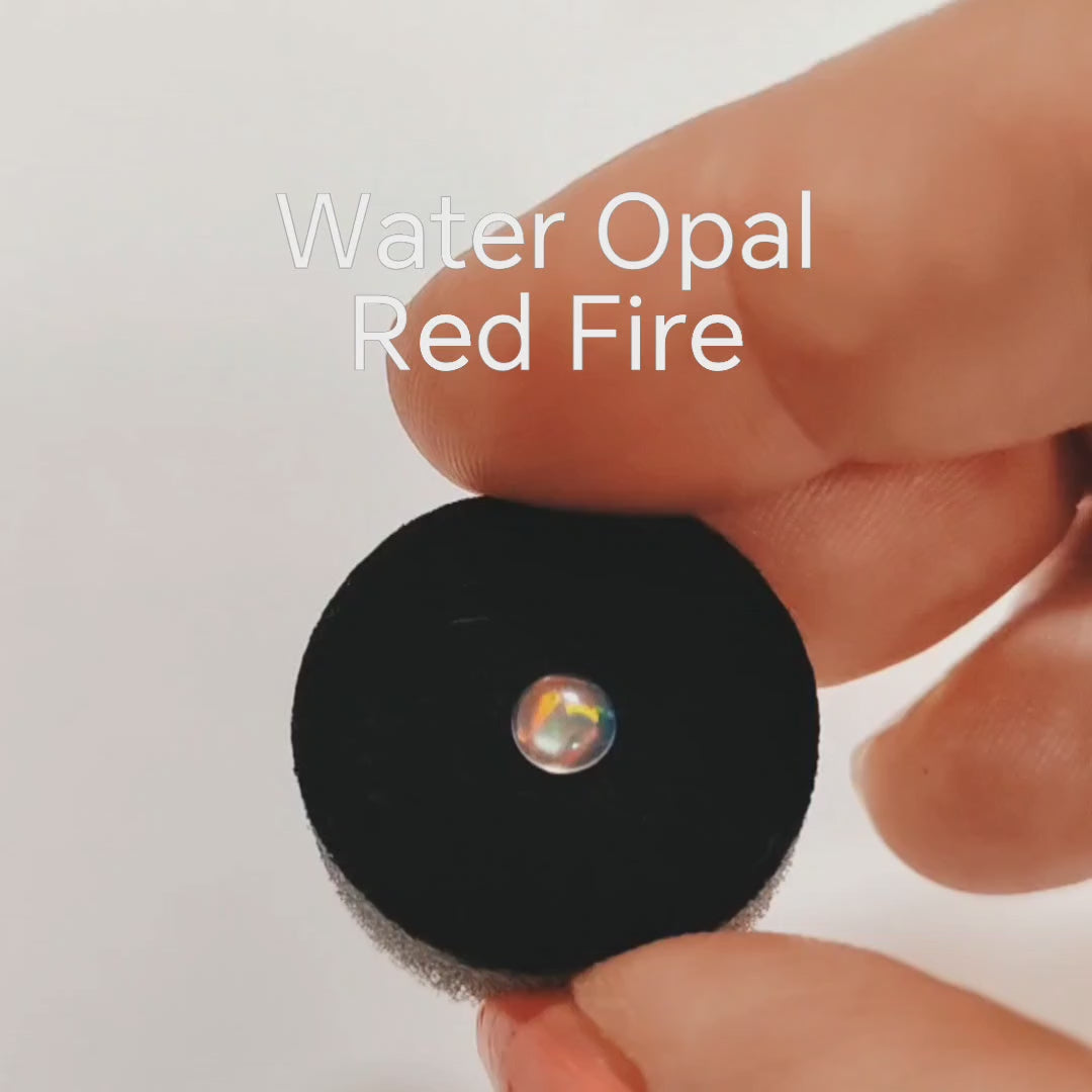 Fireable water opal with red fire on a jewellery sponge in a hand.