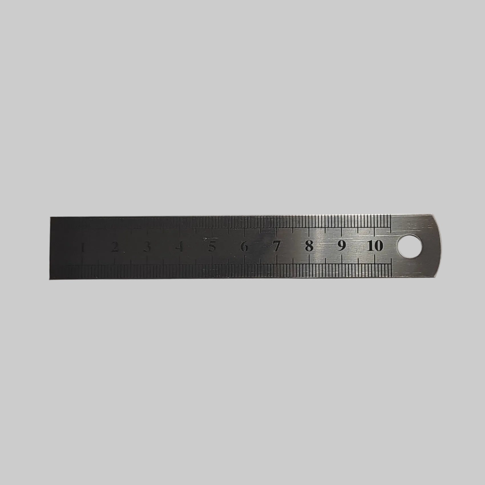 A stainless steel ruler with a 10 cm  scale and a hanging hole on one end, shown on a plain light grey background.