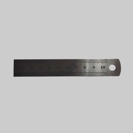 A stainless steel ruler with a 10 cm  scale and a hanging hole on one end, shown on a plain light grey background.
