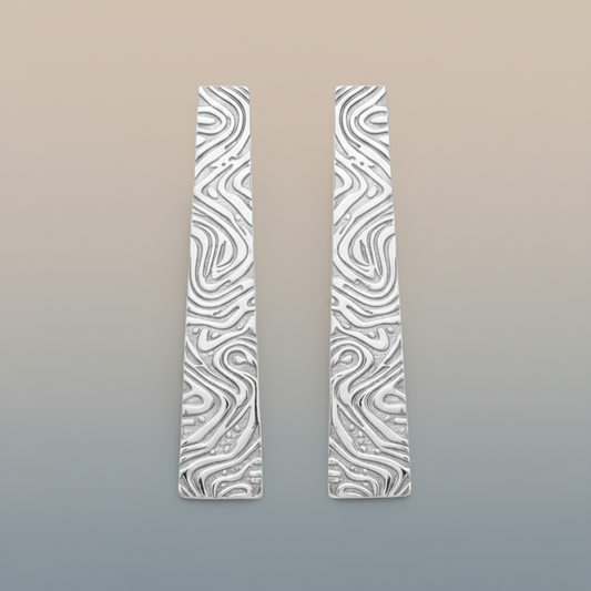 Pair of silver earrings with wavy pattern on a gradient background